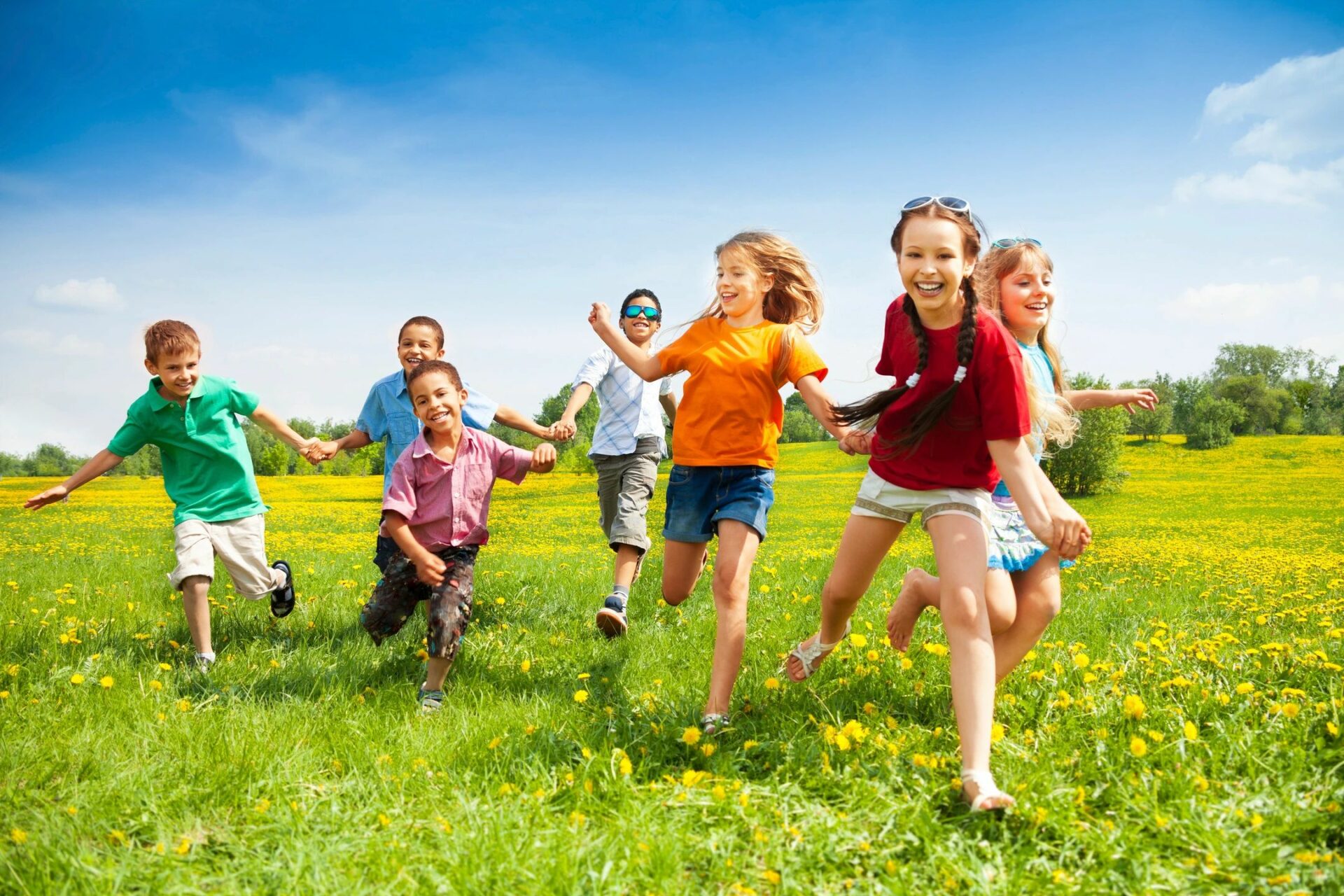 A group of children running in the grass.