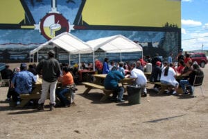 A group of people sitting at tables under tents.