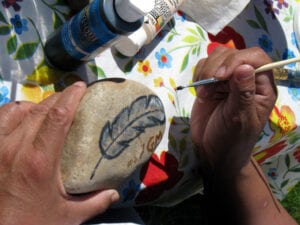 A person painting a leaf on a rock.