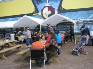 A group of people sitting at tables under a tent.