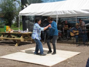 Two people dancing on a blanket in front of an outdoor tent.
