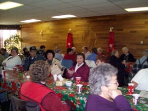 A group of people sitting at a table with christmas decorations.