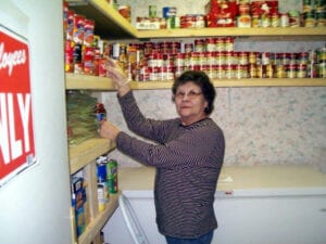 A woman is putting food in the pantry.