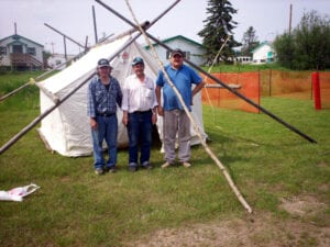 Three men standing in front of a tent.