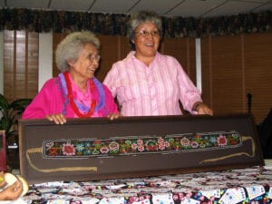 Two women standing next to a table with a quilt.