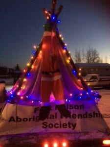 A person in a santa suit standing on top of a teepee.