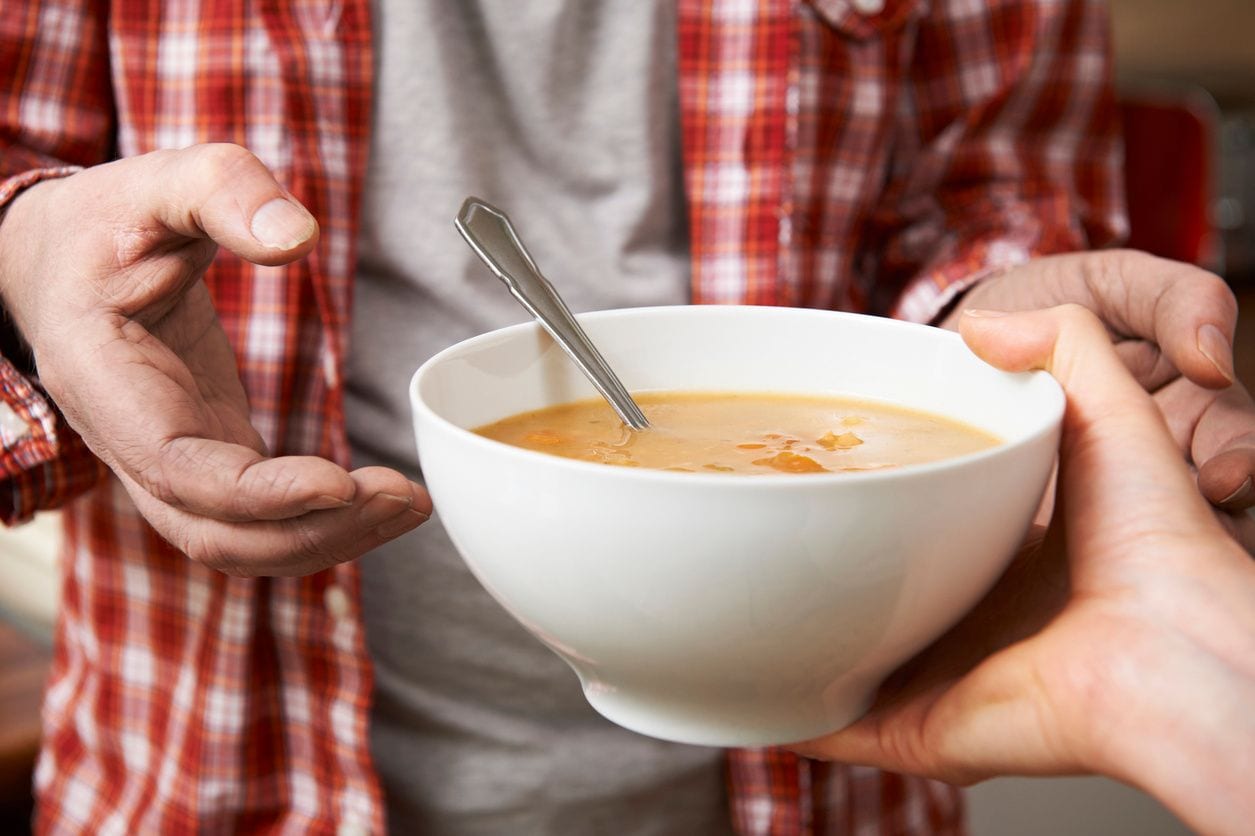 A person holding a bowl of soup in their hands.