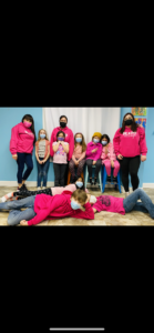 A group of people wearing pink shirts and masks.