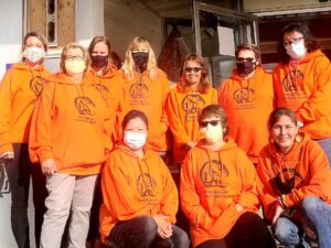 A group of people wearing orange shirts and masks.